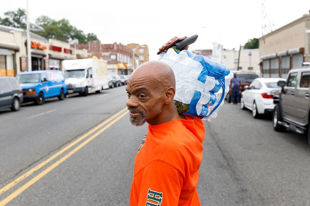 A man carries a package of bottled water he picked up at a city-run bottled water distribution site at a community center in Newark, New Jersey, August 16, 2019.